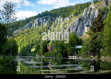 Idyllischer Blick auf das Dorf Markt Essing in Bayern, Deutschland mit der Altmühl und hohen Klippen an einem sonnigen Tag im Frühjahr Stockfoto