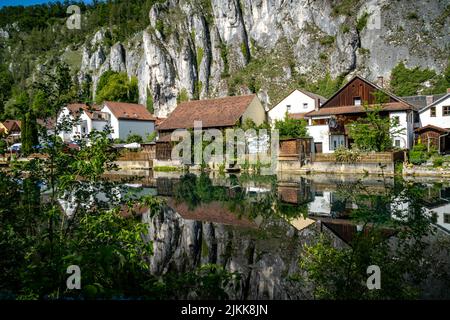 Idyllischer Blick auf das Dorf Markt Essing in Bayern, Deutschland mit der Altmühl und hohen Klippen an einem sonnigen Tag im Frühjahr Stockfoto