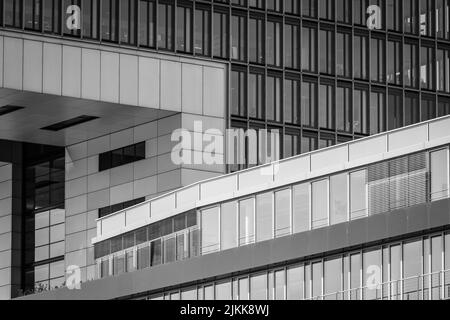 Eine Graustufe eines Gebäudes mit Glaswänden in einer Stadt Stockfoto