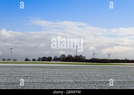 Ein kühlender Blick auf Windkraftanlagen im verschneiten Feld in Bad Homburg, Deutschland Stockfoto