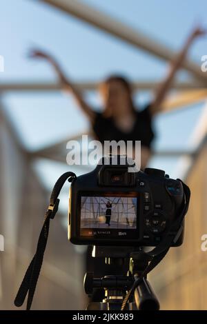Vertikales Bild einer Kamera, die eine Tänzerin aufzeichnet, die auf der Straße tanzt und sich für soziale Medien und Online-Kurse filmt Stockfoto