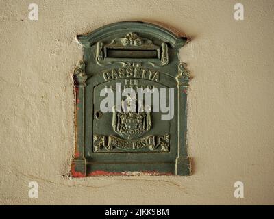 Antiker Briefkasten mit Rostspuren, der in die weiße Wand eines alten Gebäudes eingebaut ist.Inschrift besagt: Briefkasten, königliches Postsystem. Stockfoto