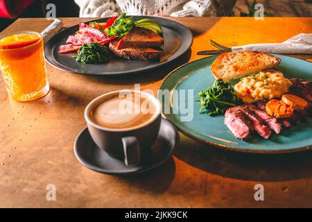 Eine Nahaufnahme eines köstlichen Mittagessens auf einem Tisch mit Orangensaft und einer Tasse Kaffee Stockfoto