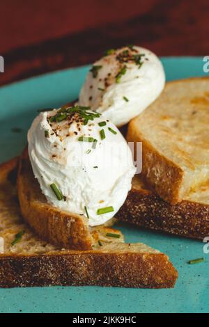 Eine vertikale Aufnahme von Toast mit gekochten Eiern auf einem hellblauen Teller Stockfoto