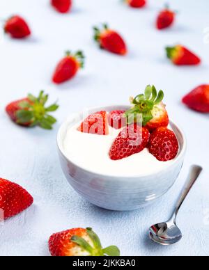 Creme-Dessert mit Erdbeerfrucht in einer Schüssel auf blauem Hintergrund Stockfoto