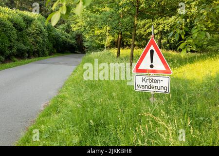 schild mit deutschem Text krötenwanderung, in englisch Migration kröde Crossing Stockfoto