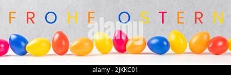 Bunte ostereier mit grauem Hintergrund und deutschem Text frohe ostern, in englischer sprache Happy easter Stockfoto