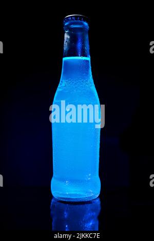 Die Flasche blauen Wassers auf dem reflektierenden Hintergrund Stockfoto