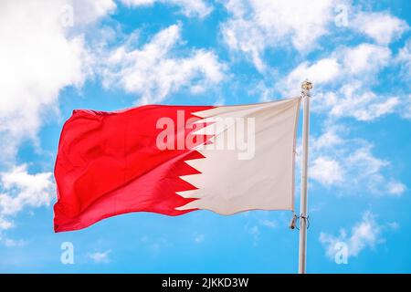 Die Nationalflagge Katars flattert im Wind auf einem Fahnenmast vor blauem Himmel Stockfoto