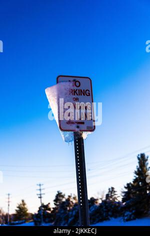 Eine vertikale Aufnahme eines No Parking-Schilds auf blauem Himmel Stockfoto