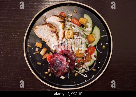 Ein Blick von oben auf einen köstlichen Keilsalat mit Fleisch und Gemüse auf einem Teller Stockfoto