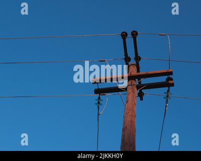 Eine alte hölzerne elektrische Stange gegen den wolkenlosen Himmel Stockfoto