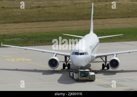 Der Flugzeugschlepper schiebt den Jet aus der Parkposition nach hinten Stockfoto