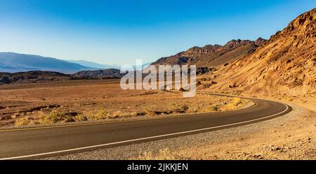 Eine Straße, die an einem sonnigen Tag durch das Death Valley in Kalifornien führt Stockfoto