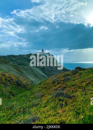 Eine Hügellandschaft mit einem Leuchtturm an einer sonnigen, bewölkten Küste Stockfoto