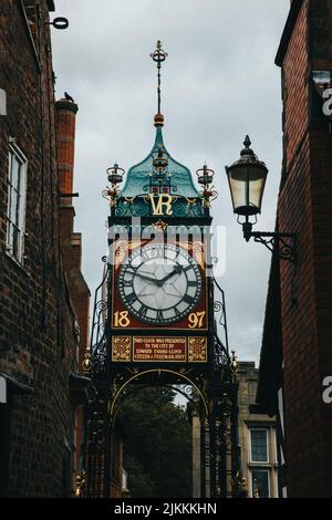 Eine vertikale Nahaufnahme der Eastgate Clock gegen einen bewölkten Himmel in Chester, England Stockfoto