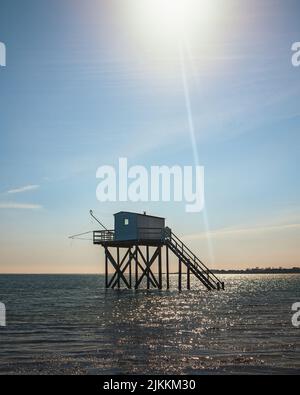 Eine vertikale Aufnahme einer traditionellen Fischerhütte im Wasser auf der Insel Aix, Frankreich, gegen einen blauen, sonnigen Himmel Stockfoto