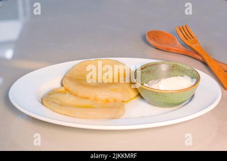 Kartoffeln Knödel mit Saus auf dem Teller und Holzlöffel und Gabel, fertig zum Essen. Stockfoto