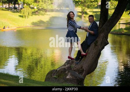 Ein süßes lettisches Paar, das auf einem Baum in einem Park steht Stockfoto
