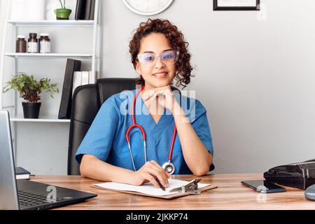 hispanische Ärztin mit Augenlicht im Klinikbüro und Blick auf die Kamera. Stockfoto
