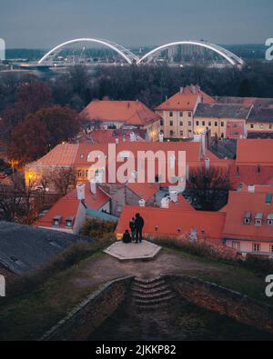 Eine vertikale, hochwinkelige Aufnahme einer Familie, die am Aussichtspunkt über den roten Dächern der Stadt steht Stockfoto