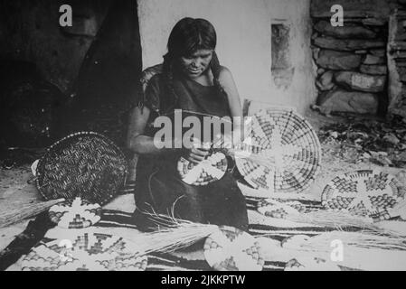 Historische Schwarz-Weiß-Fotografie einer Hopi Pueblo-Frau, die traditionelle Korbschalen webt Stockfoto