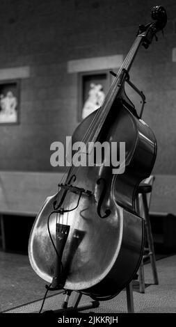 Eine vertikale Graustufenaufnahme eines Cellos auf einem Ständer Stockfoto