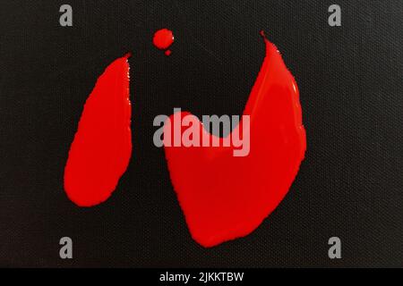 Die rote Farbe fällt auf eine schwarze Leinwand Stockfoto