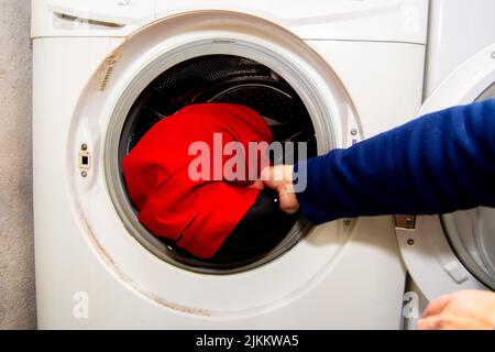 Eine Hand einer Frau, die in einer Waschmaschine Wäsche macht Stockfoto