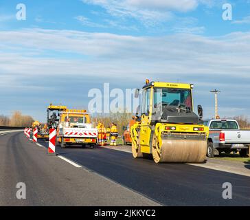 Nyiregyhaza, Ungarn – 12. Dezember 2021: Straßenarbeiten auf der Autobahn. Asphaltwalze BOMAG und andere Ausrüstung Stockfoto