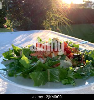 Eine Nahaufnahme eines vegetarischen Salats mit Gemüse und Tomaten auf einem Teller im Freien bei Sonnenlicht Stockfoto