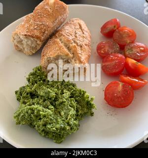 Ein Blick von oben auf einen Laib Brot mit Tomaten und Pesto-Sauce auf einem Teller Stockfoto