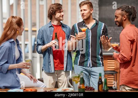 Portrait von zwei jungen Männern, die eine Dinner-Party im Freien mit verschiedenen Freunden veranstalten Stockfoto