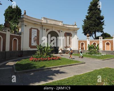 Eingang zur Ausgrabungsstätte Herculaneum in. Ercolano, Kampanien, Italien, mit drei Touristen besuchen die Website Stockfoto