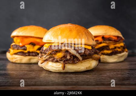Eine Nahaufnahme von leckeren saftigen Burgern auf einem Holztisch Stockfoto