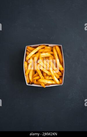 Eine vertikale Draufsicht auf einen Behälter mit leckeren Pommes auf einer grauen Oberfläche Stockfoto