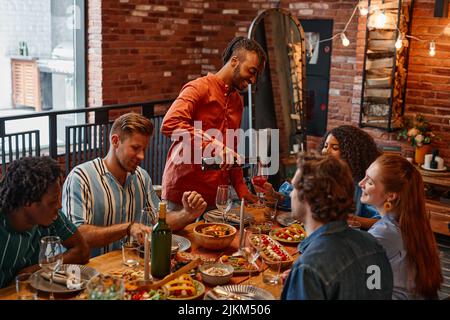 Warme, getönte Aufnahme von verschiedenen Freunden, die in einer gemütlichen Hütte eine Abendparty genießen Stockfoto