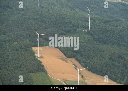 Collenberg, Bayern, Deutschland, 10. Juli 2022 Windenergieanlagen rotieren auf einem grünen Hügel, von einem kleinen Flugzeug aus gesehen Stockfoto