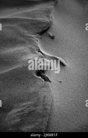 Eine Graustufenaufnahme des Sandes in der Wüste Stockfoto