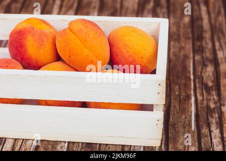 Frische, exotische Aprikosen in Holzkiste auf Holzhintergrund. Stockfoto