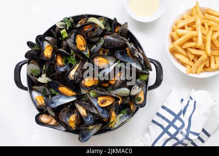 Eine Draufsicht auf belgische Muscheln mit gebratenen Pommes frites und Sauce auf einem weißen Marmortisch Stockfoto