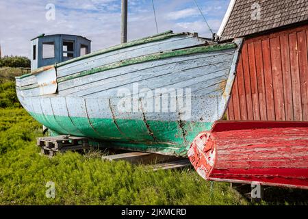 Alte bunte rote, grüne und blaue Fischerboote mit abblätternder Farbe an Land in Sisimiut, Grönland, am 16. Juli 2022 Stockfoto
