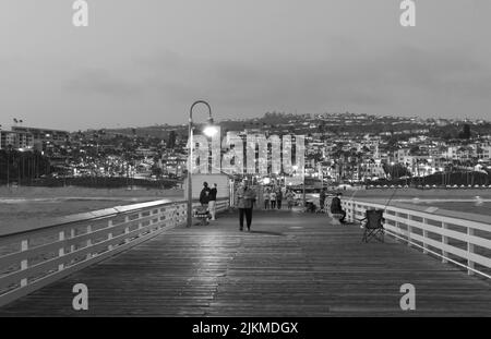 Eine Graustufenaufnahme des San Clemente Pier mit Menschen, die herumlaufen Stockfoto