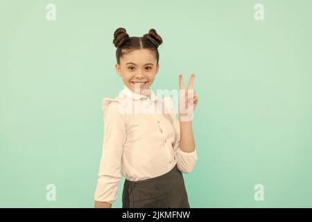 Friedensstifter. Kinder im Schulalter zeigen V-Schild. Happy Kid blauen Hintergrund. Grundbildung. Zurück zur Schule Stockfoto