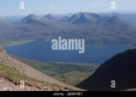 Ein herrlicher Blick auf einen ruhigen See, umgeben von grünen Hügeln unter einem hellen Himmel an einem sonnigen Tag in Schottland Stockfoto