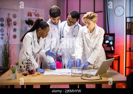 Ein vielfältiges Team von Medizinwissenschaftlern löst Probleme und blickt auf Forschungsergebnisse. Neurologen oder Neurowissenschaftler, die im Forschungslabor des Gehirns arbeiten. Stockfoto