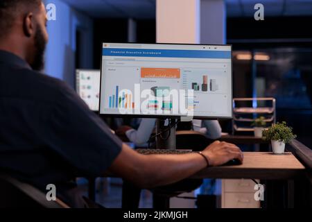 Executive Manager, der Computermonitor mit Diagrammen betrachtet, statistische Informationen und Daten analysiert, um einen Projektbericht zu erstellen, Finanzforschung durchführt. PC-Bildschirm mit Netzwerkdarstellung. Stockfoto