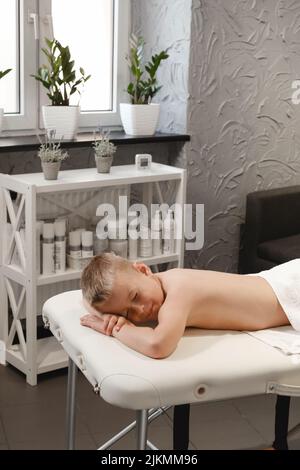 Kind nach Rückenmassage Behandlung in der Therapieklinik entspannend. Kid Body Treatment, Spa und Gesundheitskonzept. Schmerzlinderung. Humaner Rücken, Junge Wirbelsäule Kopie Stockfoto