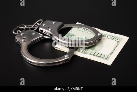 Betrug und Geldwäsche, Handschellen und Dollar. Stockfoto