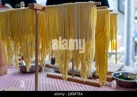 Ein Porträt von frisch zubereiteter Pasta, die auf einem Nudeltrockner hängt Stockfoto